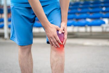 Diseases of the knee joint, bone fracture and inflammation, athletic man on a running track after workout suffering from pain in leg and doing self-massage - 754200441