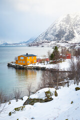 Idyllic view of a classic yellow colored Norwegian house on the shore of a fjord in northern Norway