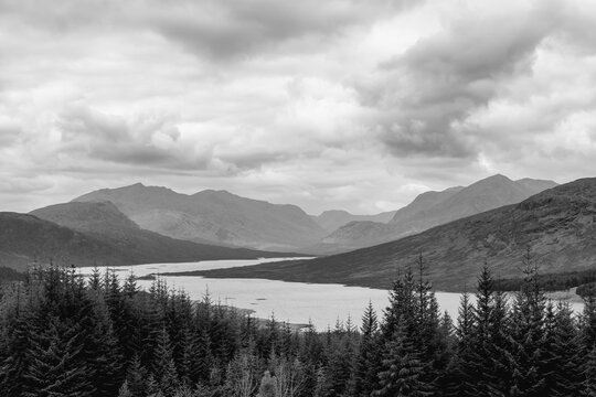 Overlooking Loch Loyne, this grayscale landscape showcases the rugged beauty of the Scottish Highlands, with layered mountain ranges under a textured sky
