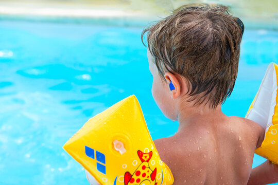 enfant avec des bouchons d'oreille &agrave; la piscine, pr&eacute;vention otite 