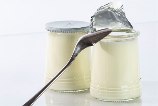 yaourts en pot en verre, avec une cuill&egrave;re, sur fond blanc