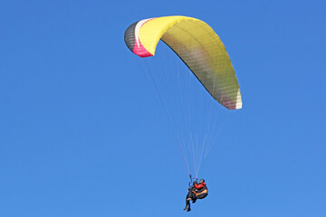 Tandem Paraglider flying in a blue sky	