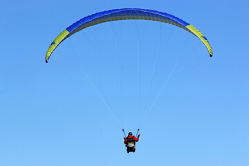 Paraglider flying in a blue sky	
