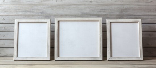 Three white picture frames are showcased on a wooden shelf against a textured concrete backdrop. The frames are empty, waiting to display art or photographs.