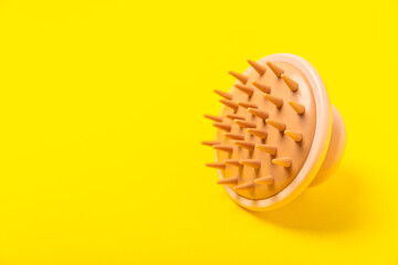 Brush for scalp massage on a yellow background. Brush for hair growth stimulating brush. Hair massage. stimulating brush. Hair care, head relaxation concept. Copy space.