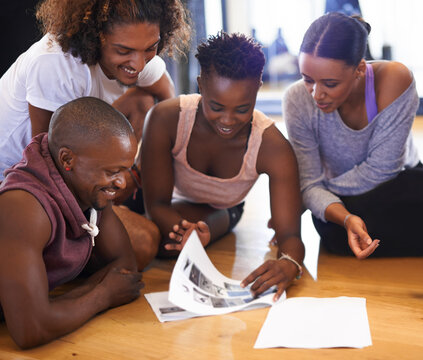 Dancer, talking and group on floor with people reading paper, catalog or review of dancing. Students, learning and conversation in studio of academy with article on ground with happy discussion - Powered by Adobe
