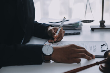 Justice and Law concept. Legal counsel presents to the client a signed contract with gavel and legal law or legal having team meeting at law firm in background