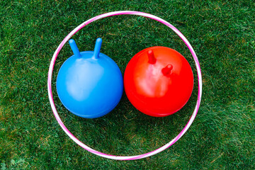 childhood, leisure and toys concept - bouncing balls or hoppers and hula hoop on grass - 754222209
