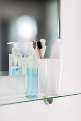 hygiene, beauty and daily routine concept - close up of lotion, toothbrush and toothpaste on mirror shelf in bathroom - 754225494