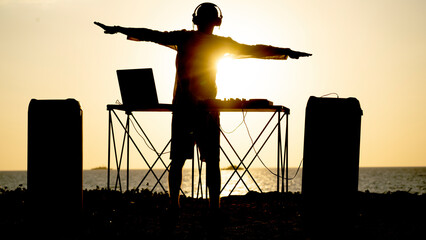 DJ on the beach at sunset plays beautiful music in
