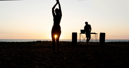 girl dancing at sunset by the sea to the music of a DJ in