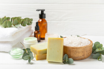 Beautiful spa composition on a wooden background with eucalyptus leaves. Beauty and fashion spa concept with body cream, scrub, mask, essential oil and sea salt.Cosmetic product. Copy space.