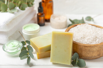 Beautiful spa composition on a wooden background with eucalyptus leaves. Beauty and fashion spa concept with body cream, scrub, mask, essential oil and sea salt.Cosmetic product. Copy space.