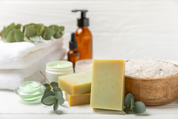 Beautiful spa composition on a wooden background with eucalyptus leaves. Beauty and fashion spa concept with body cream, scrub, mask, essential oil and sea salt.Cosmetic product. Copy space.