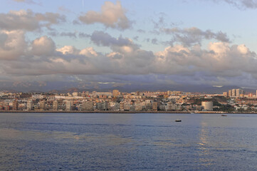 Small Boats in the calm water in front of the shoreline of Las Palmas as a Vessel heads into the...