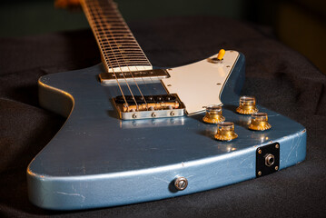 A well used looking blue Theta guitar resting on a black cloth
