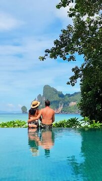 A couple sits in an infinity pool by the ocean, immersed in the breathtaking view of water, sky, and natural landscapes. A perfect setting for relaxation and serenity