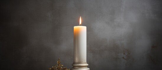 A white candle is burning brightly on top of a wooden table. The flame casts a warm glow in the room, illuminating its surroundings.