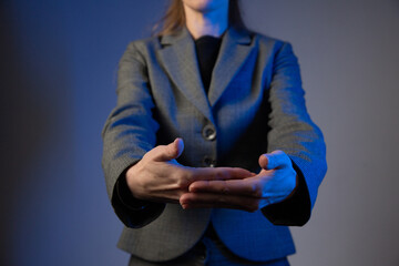 A business woman holds her hands outstretched forward, palms facing each other. No face. Blue color correction