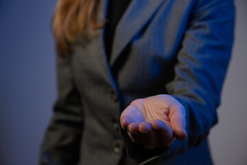 Part of a business woman with her arm extended forward and palm up close-up. Gray background. Blue...