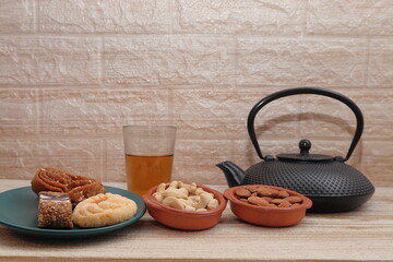vaso de te tetera oscura fondo ladrillo claro almendras anacardos
