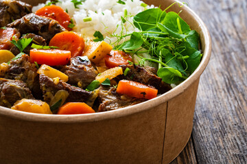 Takeaway food - roast pork with carrots and celeriac in sauce with white rice in lunch box on...