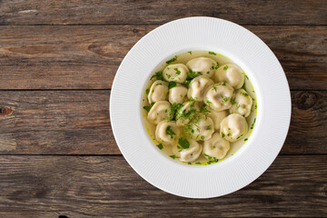 Pelmeni - dumplings filled minced meat in broth on wooden table
