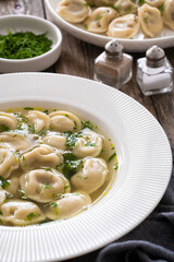 Pelmeni - dumplings filled minced meat in broth on wooden table
