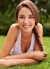Woman, portrait and smile on grass for relax with sunshine, enjoyment or weekend break in summer. Young person, happiness or confident on lawn, garden or backyard of home for fresh air in environment