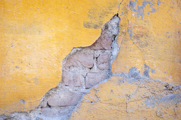 brick wall with yellow paint and peeling plaster