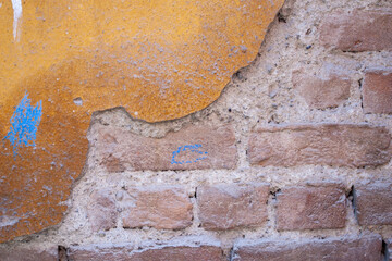 brick wall with yellow paint and peeling plaster