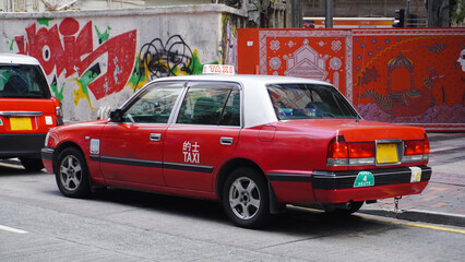 A fleet of Hong Kong taxis waiting at a taxi stand. Hong Kong taxis are easily recognizable by their red and white colors.