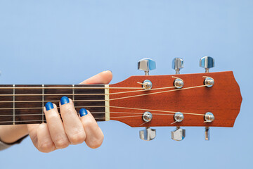 female fingers pinch the strings on a guitar
