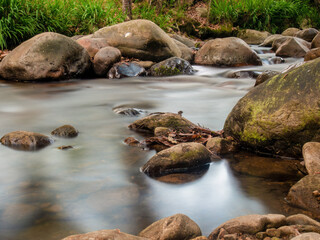 Naklejka na ściany i meble Long exposure shot of the stream and the rocks in the La Colorada creek, in the eastern Andean mountains of central Colombia.