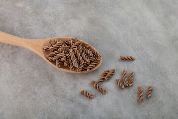 Pasta di Lino or Flaxseed gluten free pasta in spoon on grey background, close-up. Low glycemic...