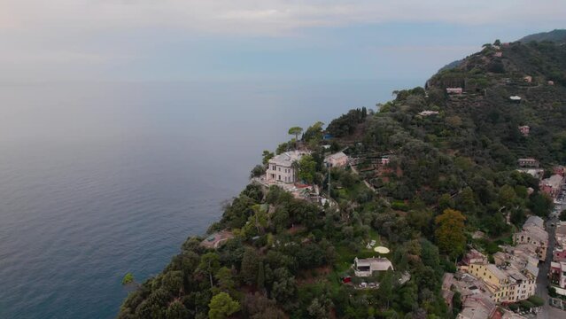 Establishing orbit drone shot of a luxury house on the cliff at Portofino Italy. Blue sky, colorful houses, turquoise water