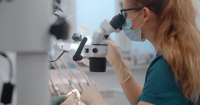 Portrait of the dental surgeon using the microscope during the surgery in dental clinic