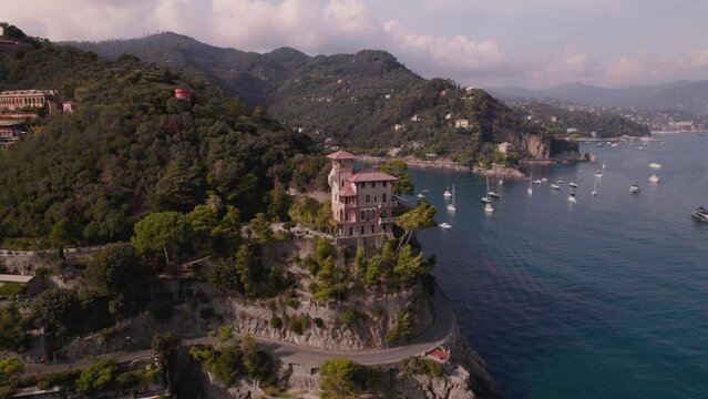 Establishing shot of a historic Italian house on a cliff in Portofino Italy. The house located on a hill surrounded by the Ligurian turquoise color waters