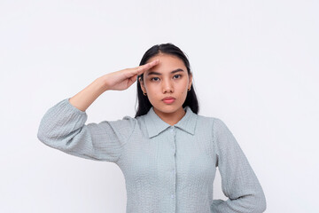 Asian young adult woman performing a respectful salute gesture, showcased in a studio setting with...