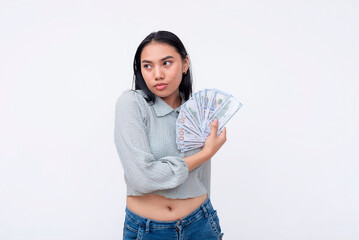 Portrait of a young Asian woman confidently displaying a bunch of hundred dollar bills, symbolizing...