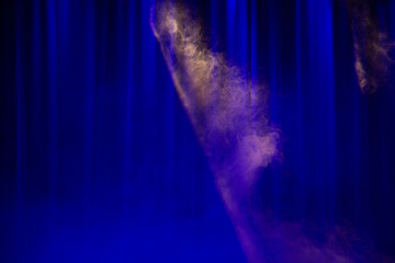 Plumes of smoke in a spotlight against the background of a stage curtain
