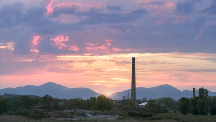High industrial chimney in Miranda de Ebro, Burgos, before a sky with warm colored clouds at sunset