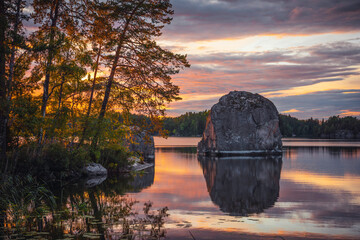 sunset on the lake with a large boulder