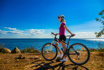  Beautiful young woman riding bicycle at seaside
