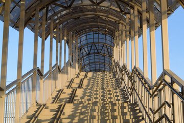 View from below on the stairs of the pedestrian bridge in the light of the sun at sunset