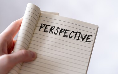Female hand holding an open notebook with the word Perspective written on it.