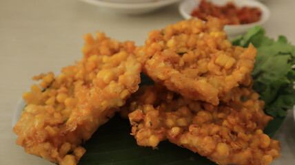 Crispy fried corn balls in white plate on wooden table, vegetarian food.
