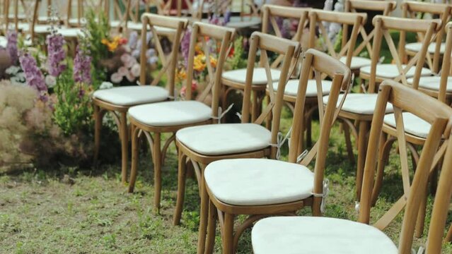 Row of wooden chairs on grassy field, blending with natural landscape. Wedding day