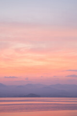 Vertical image Pastel sunset over tranquil lake and mountains.