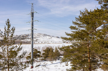 power line in a mountainous area among trees in winter at sunny afternoon
